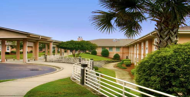 Lexington Health Extended Care's grassy grounds with sidewalks, fences, and benches for resting.