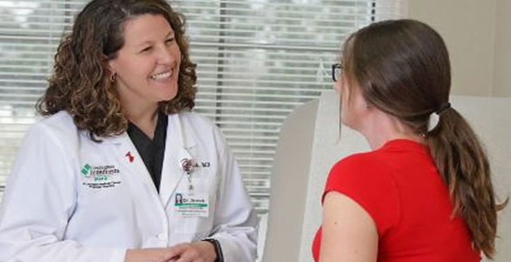 A doctor smiling at a patient in the examination room.