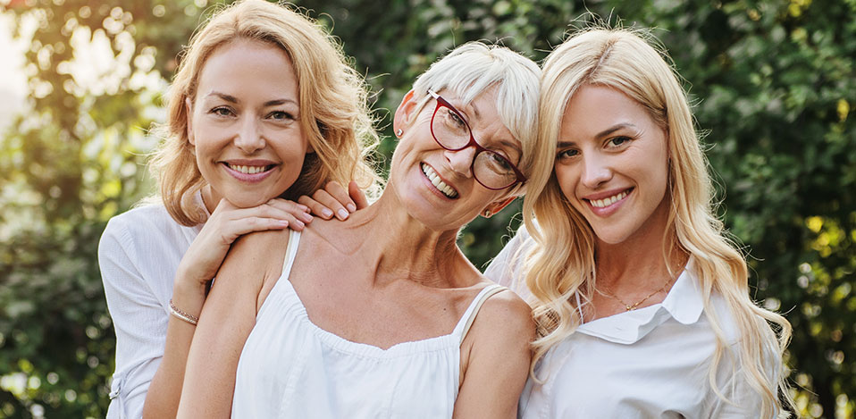 A daughter, mother and grandmother standing close together, smiling.