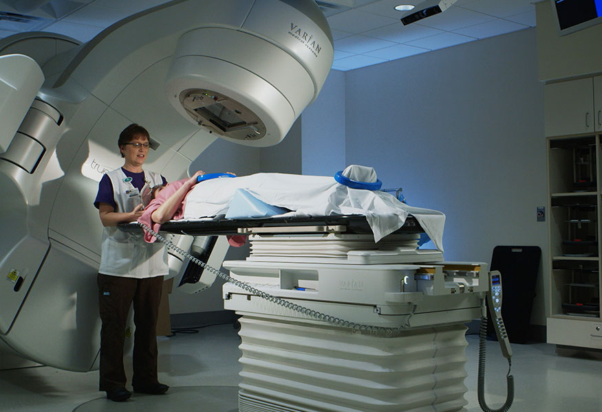 A lab technician performing an imaging procedure on a patient. 