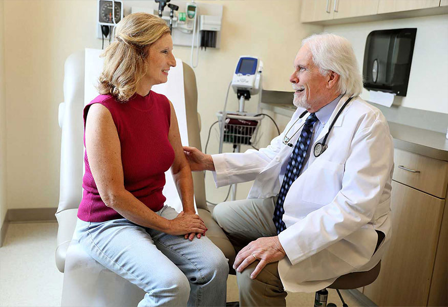 An oncologist and patient, smiling and speaking to each other.