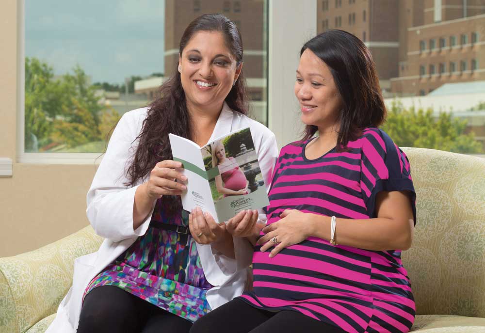 Obstetrician and pregnant patient reviewing a pamphlet together.
