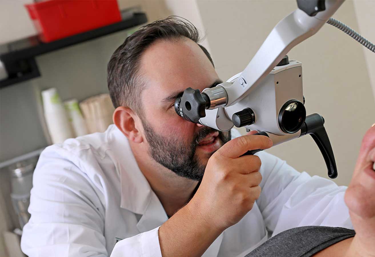 An ear, nose and throat doctor using equipment to look inside a patient's ear.