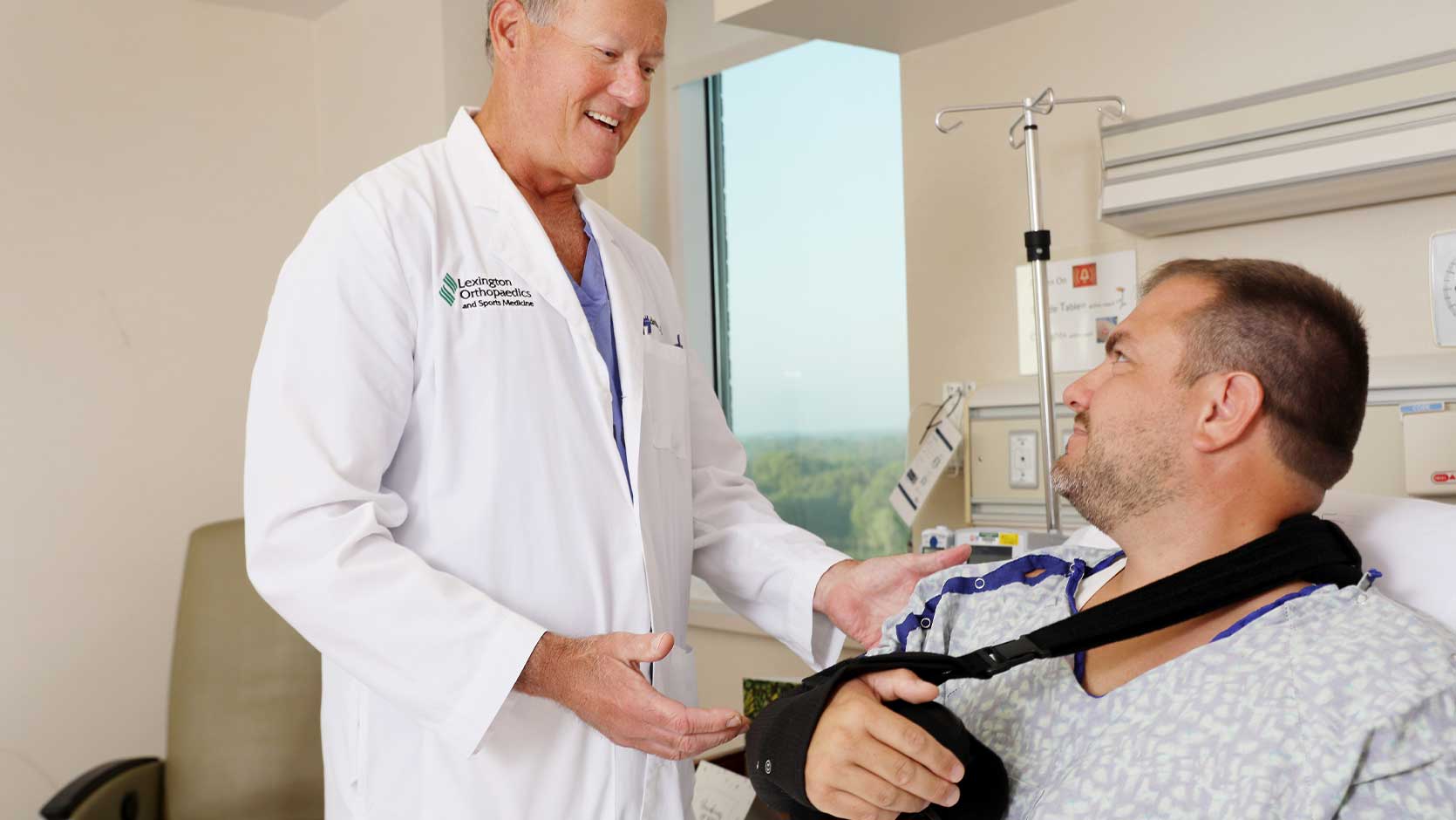 Doctor speaking to a patient wearing an arm sling.