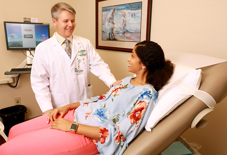 A doctor speaking to a woman in a doctors' office room. 